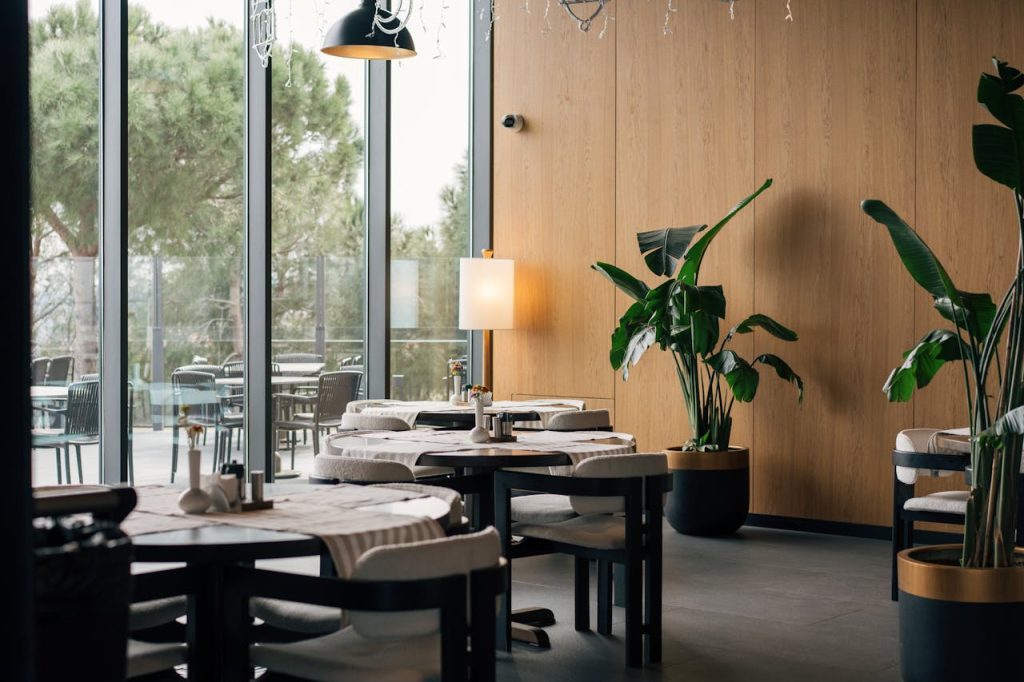 Elegant restaurant interior with modern decor in Istanbul, featuring large windows and lush greenery.